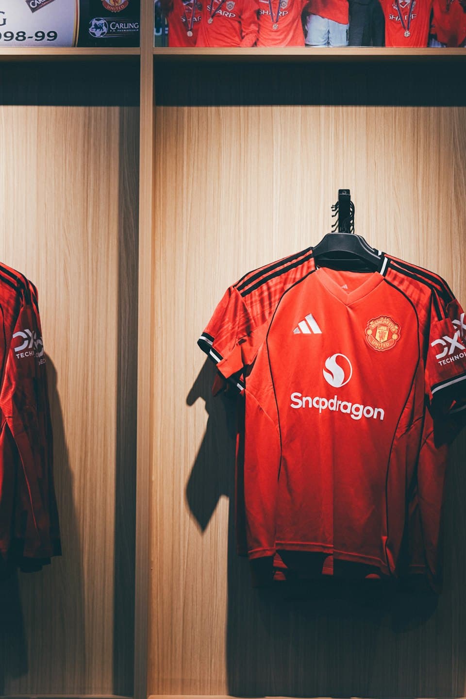 Maglie da calcio rosse appese a una parete di legno.